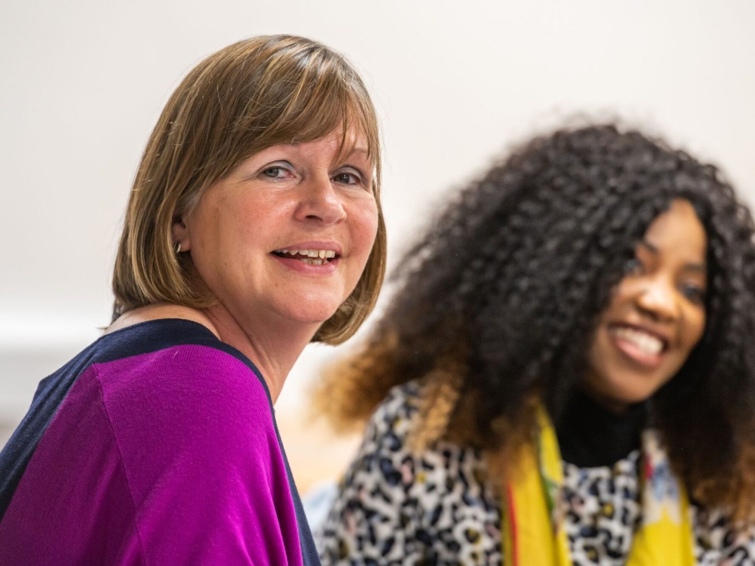 Two writers smiling during a group workshop session